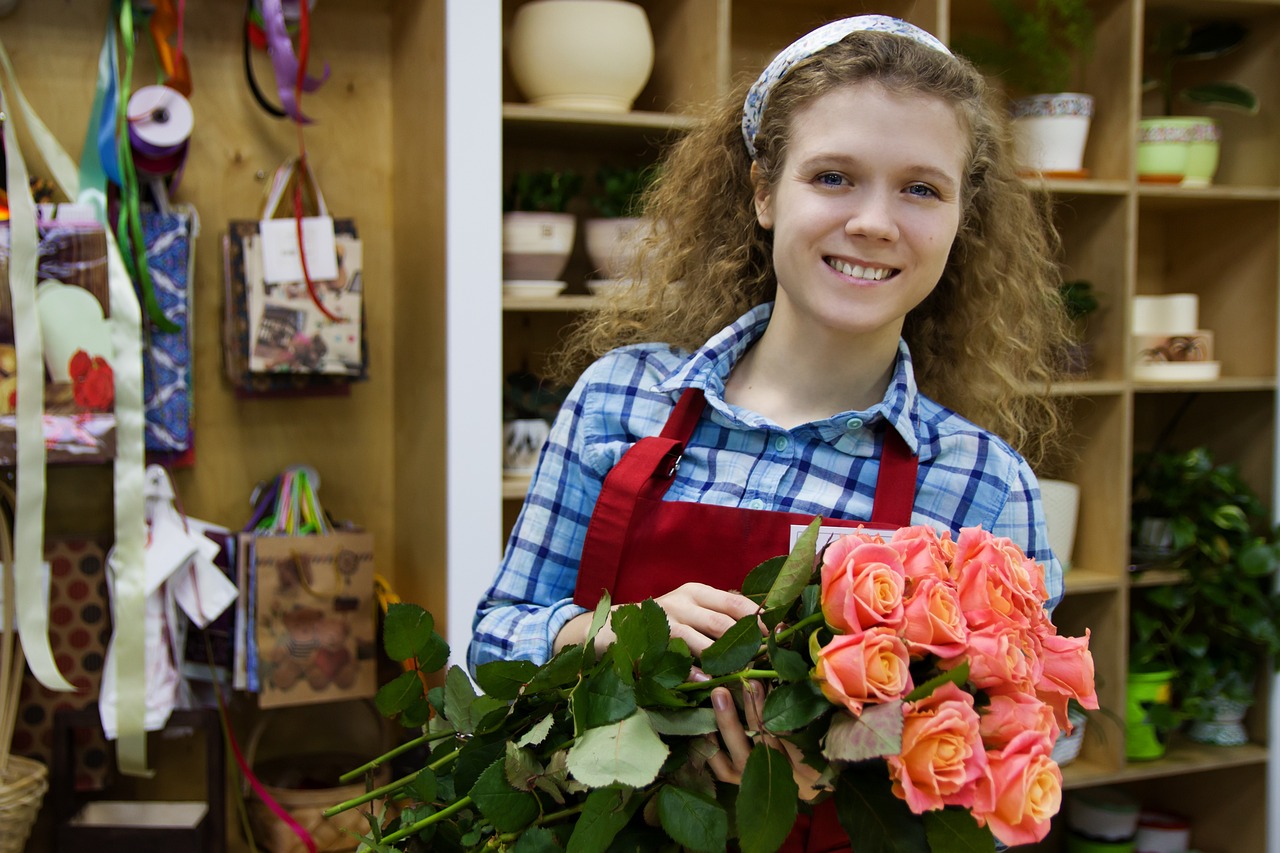 a woman standing in a flower shop holding a bunch of flowers, a portrait, by Kurt Roesch, shutterstock, teenager, wearing an apron, roses in her hair, mid shot photo