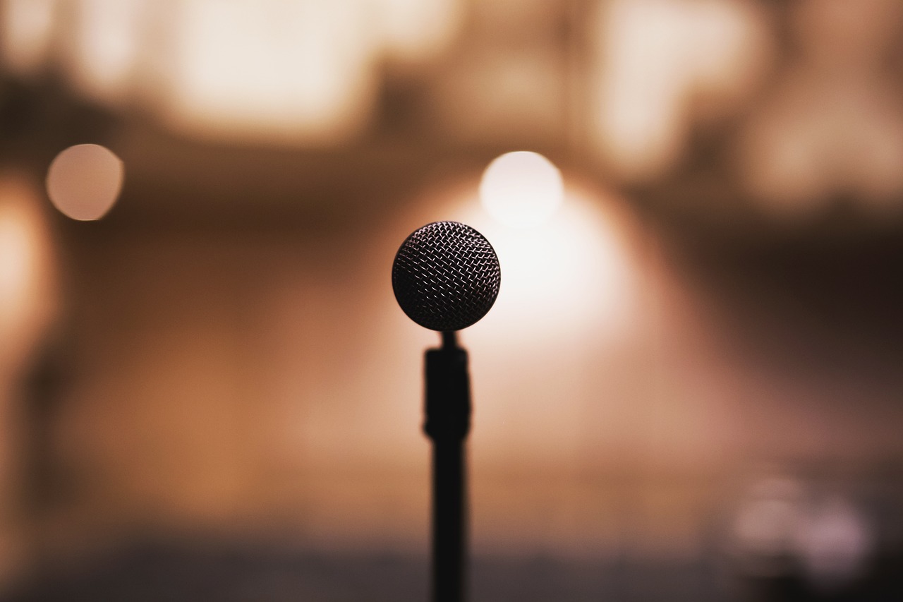 a close up of a microphone on a stand, shutterstock, dark warm light, funny, motivational, 555400831