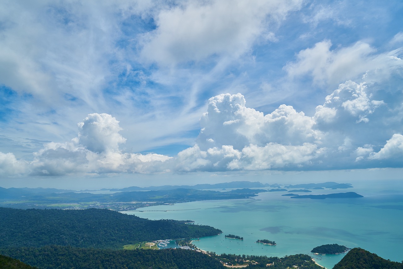 a large body of water sitting on top of a lush green hillside, by Matthias Stom, shutterstock, dramatic clouds cyan atmosphere, view from above on seascape, thailand, airborne view