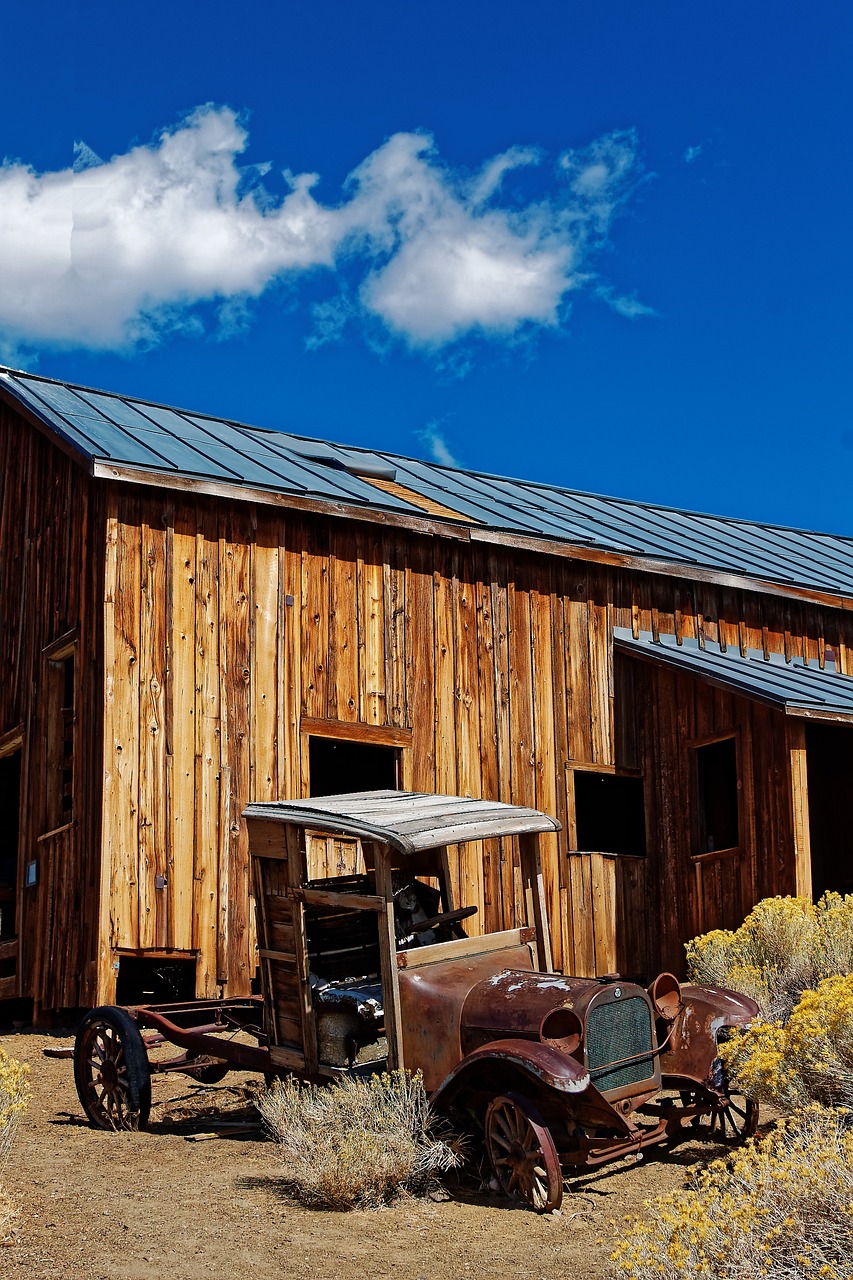 an old truck parked in front of a wooden building, shutterstock, death valley, directional sunlight skewed shot, background image, black steel buildings