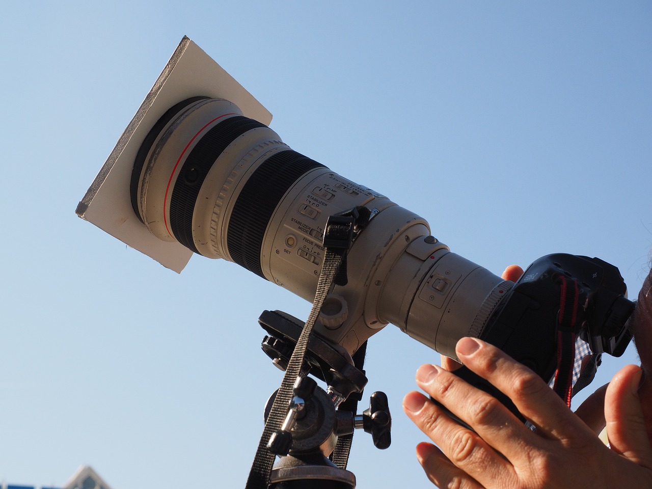 a close up of a person holding a camera, photorealism, 3 0 0 mm telephoto lens, towering over the camera, natural light canon eos c 3 0 0, behind the scenes photography