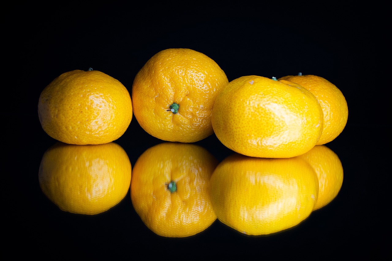 a group of three oranges sitting next to each other, by Richard Carline, mirror reflection, flash photo, black. yellow, 4 k product photo