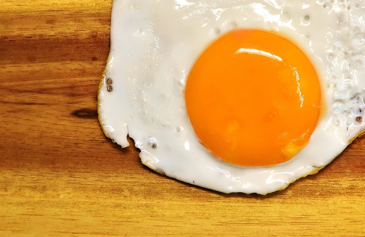 a fried egg sitting on top of a wooden table, a picture, realism, 🦩🪐🐞👩🏻🦳, super detailed image, foodphoto, close-up view