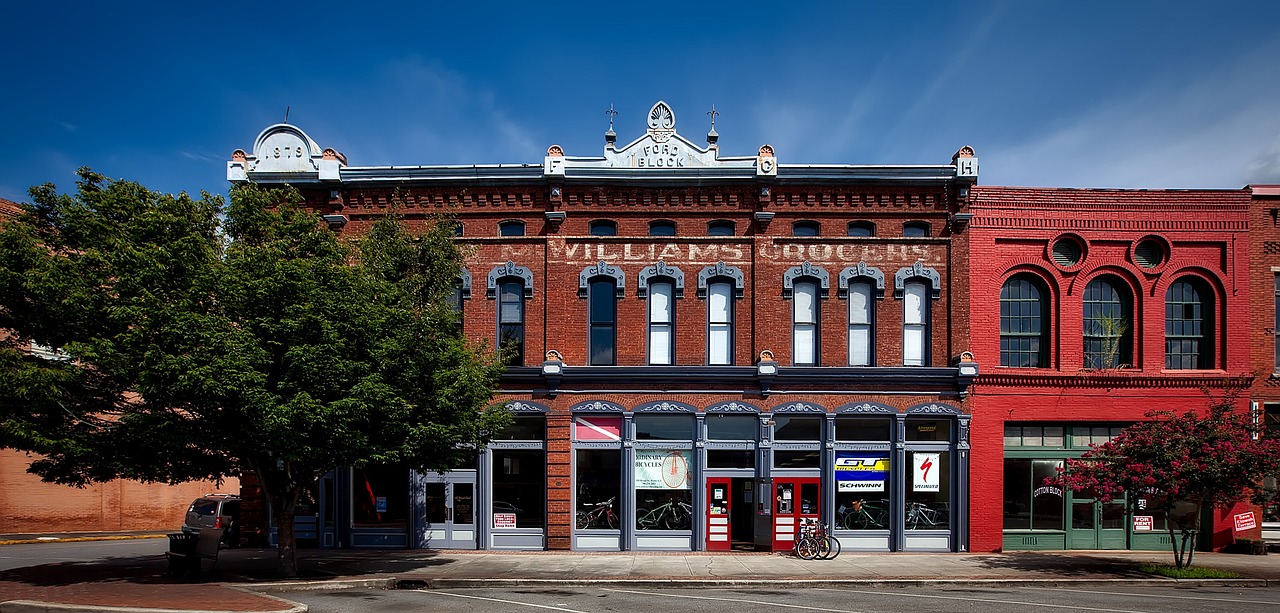 a red brick building sitting on the corner of a street, by William Woodward, flickr, folk art, colorado, victorian setting, commercial photography, walton's five and dime