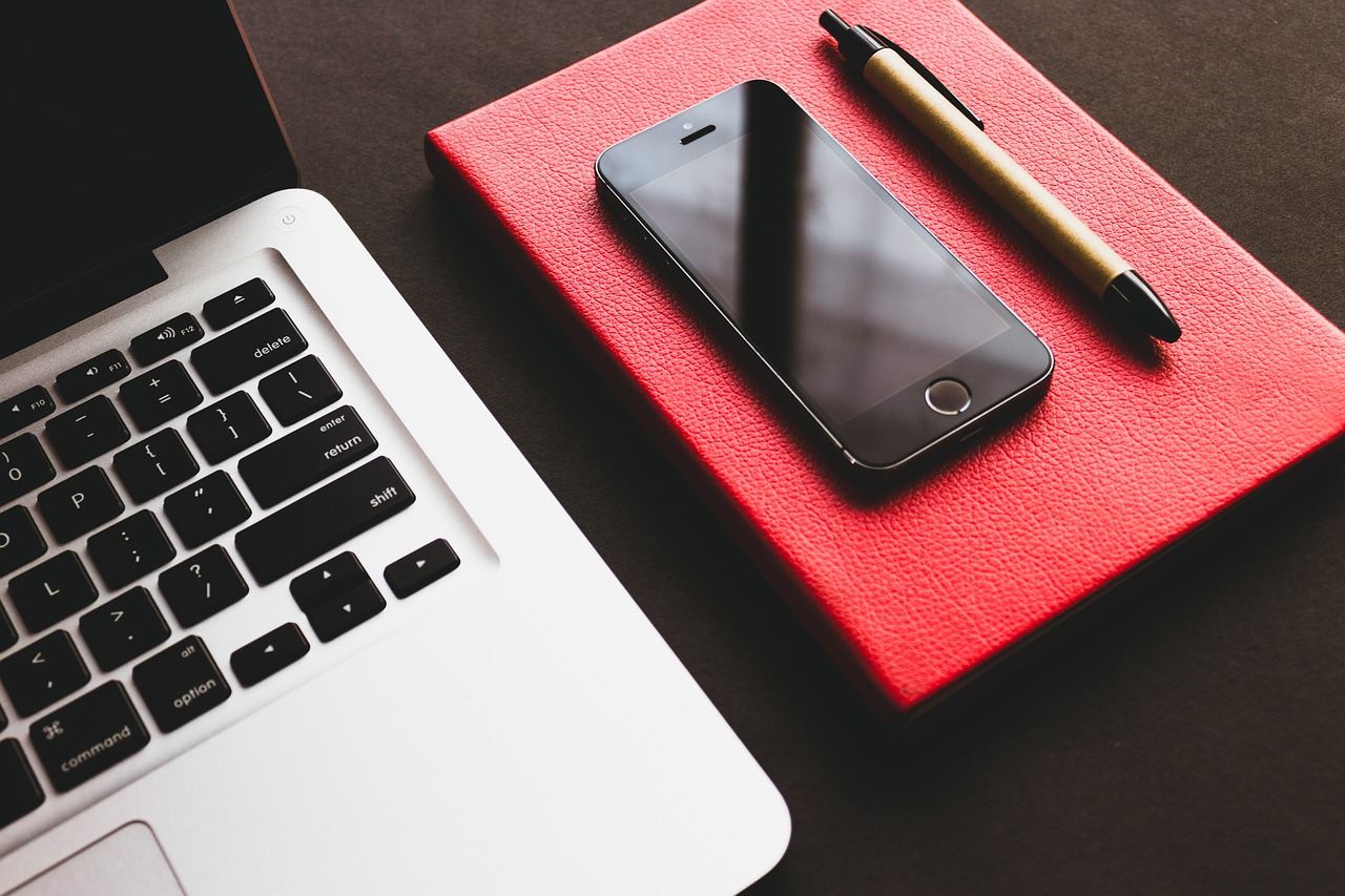 a cell phone sitting on top of a red book next to a laptop, by Romain brook, trending on pexels, red black white golden colors, professional iphone photo, working on a laptop at a desk, texture