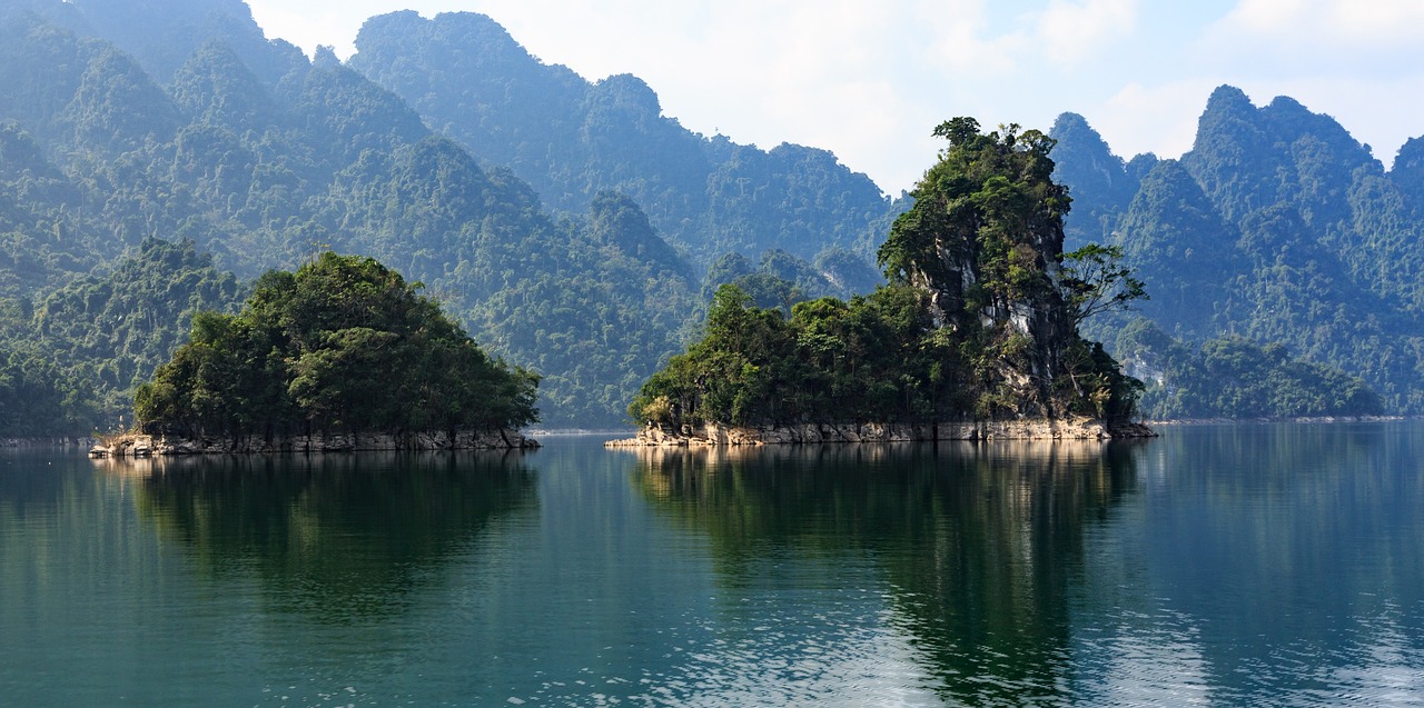 a couple of small islands in the middle of a lake, a picture, inspired by Lam Qua, shutterstock, mountainous jungle setting, filmed in 70mm, dao trong le, stunning lines