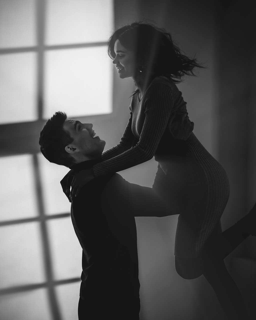 a black and white photo of a man and a woman, a portrait, tumblr, romanticism, sensual dancing, next to a big window, natural lighting. 8 k, maxim sukharev