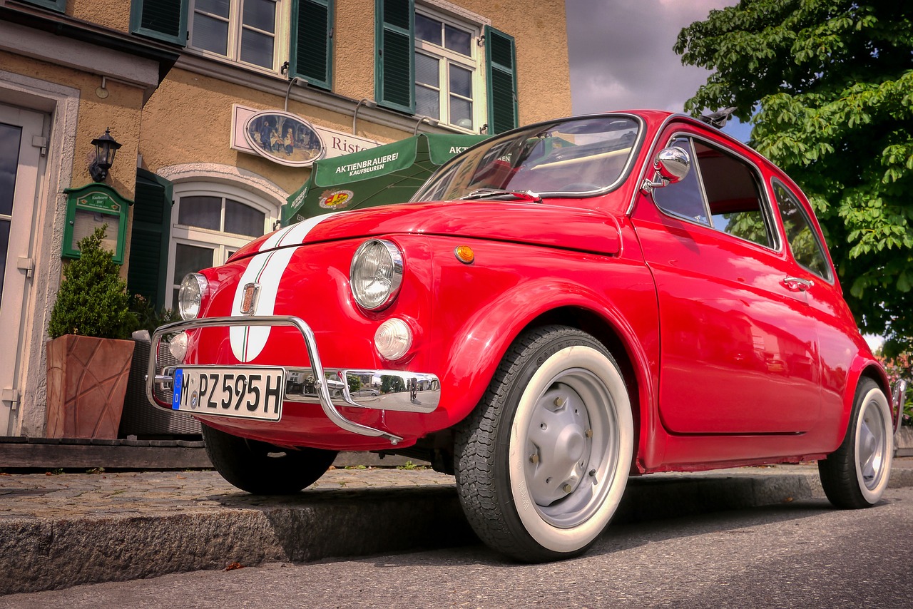 a small red car parked in front of a building, by Hans Schwarz, pixabay contest winner, photorealism, mozzarella, hdr!, looking cute, ah puch