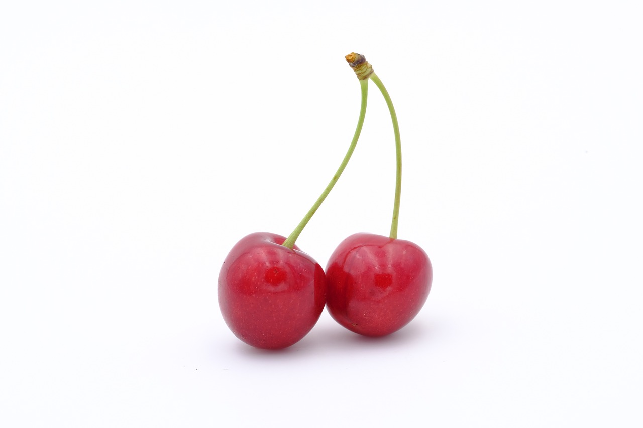 two cherries sitting next to each other on a white surface, 8 0 mm photo