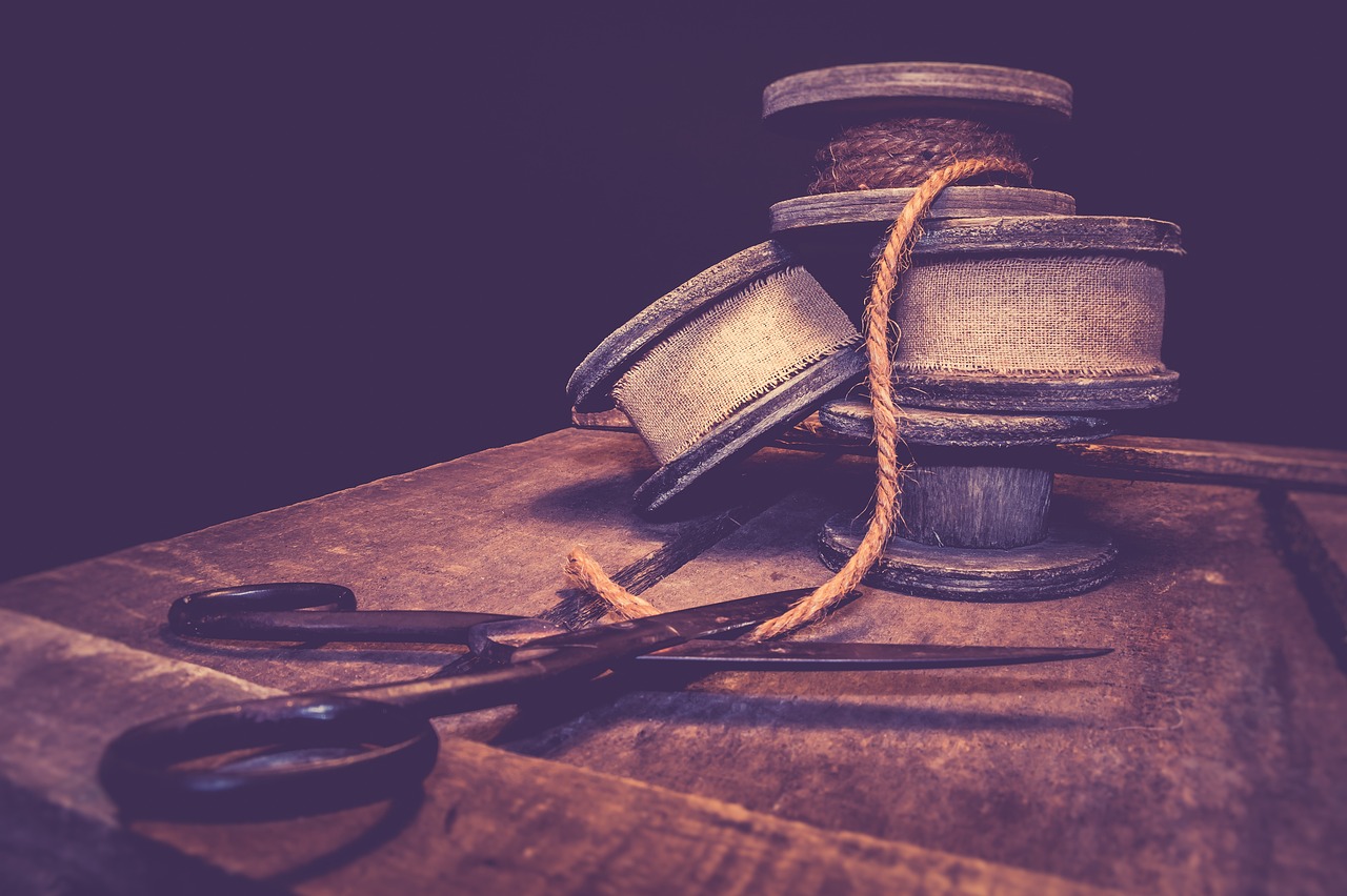 a pair of scissors sitting on top of a wooden table, a picture, by Adam Szentpétery, shutterstock, arts and crafts movement, retro dark vintage, threads, close - up studio photo, stacked image