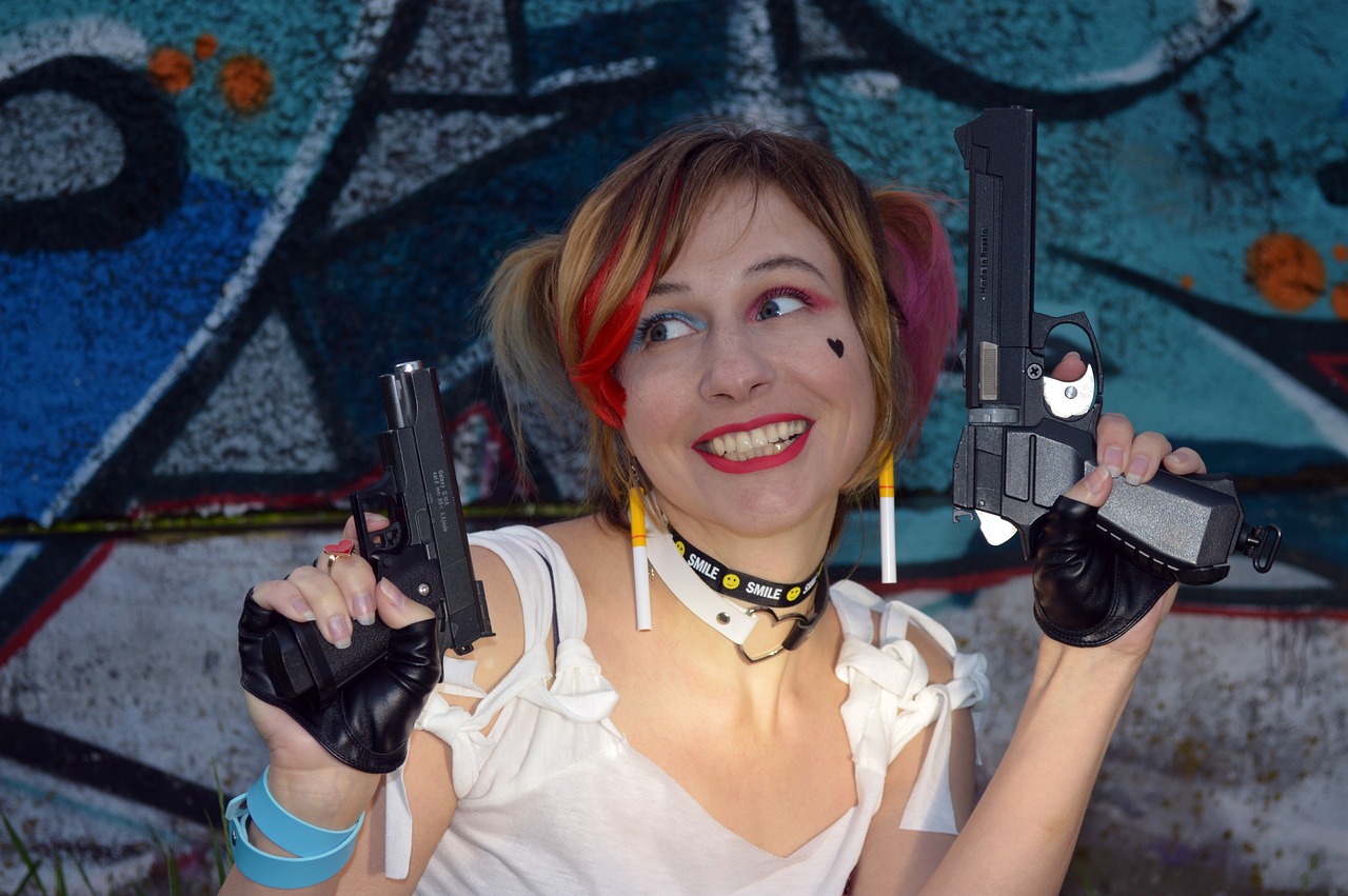 a woman holding two guns in front of a graffiti wall, a portrait, inspired by Jules Chéret, deviantart, portrait of harley quinn, closeup photo, 2 0 5 6 x 2 0 5 6, rena nounen style 3/4
