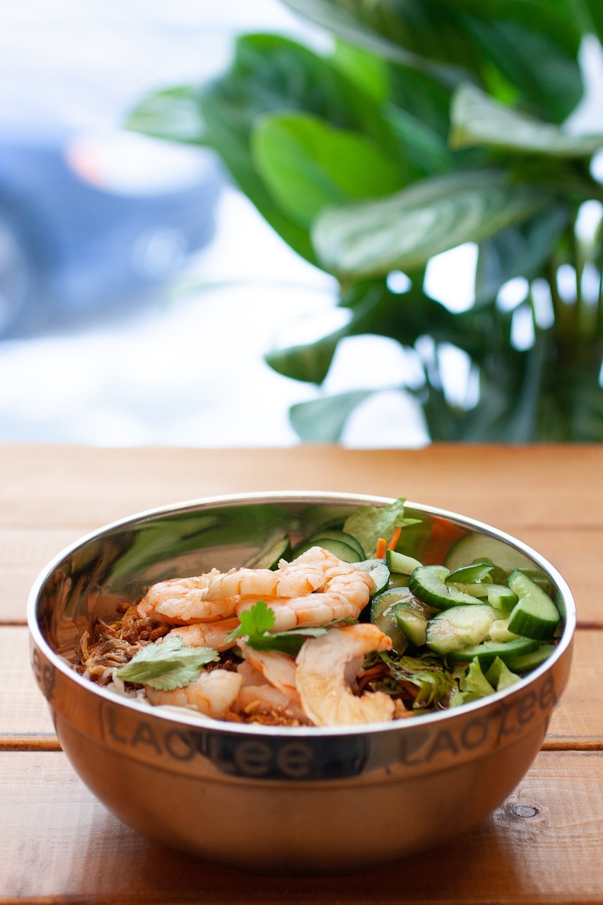 a bowl of food sitting on top of a wooden table, unsplash, shin hanga, shrimps are all over the ground, in style of lam manh, on a sunny day, 🦩🪐🐞👩🏻🦳