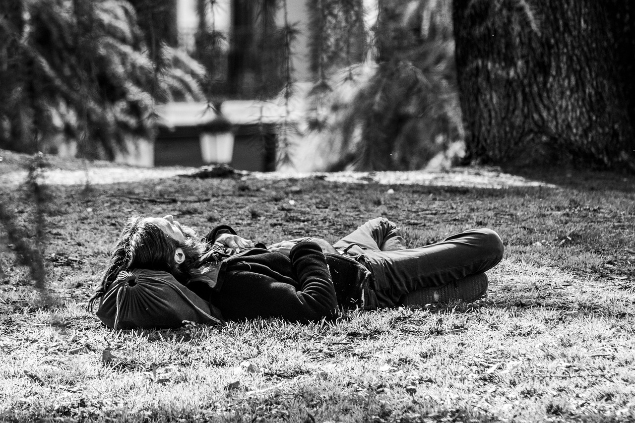 a black and white photo of a person laying in the grass, by Alessandro Allori, pexels, sunny day in a park, february), relaxing after a hard day, a man