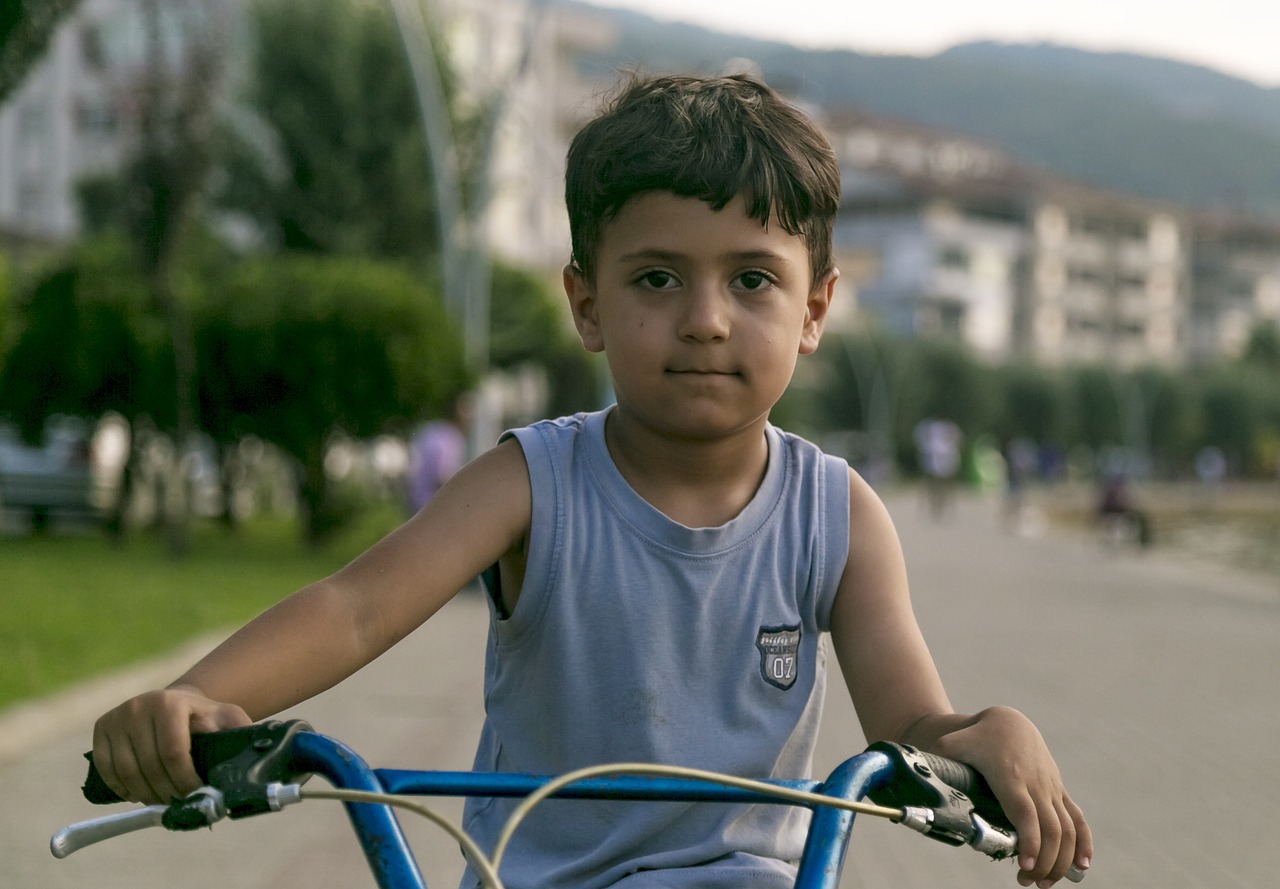 a young boy riding a bike down a street, by Alexander Fedosav, pexels contest winner, realism, large friendly eyes, turkey, square, still from a movie