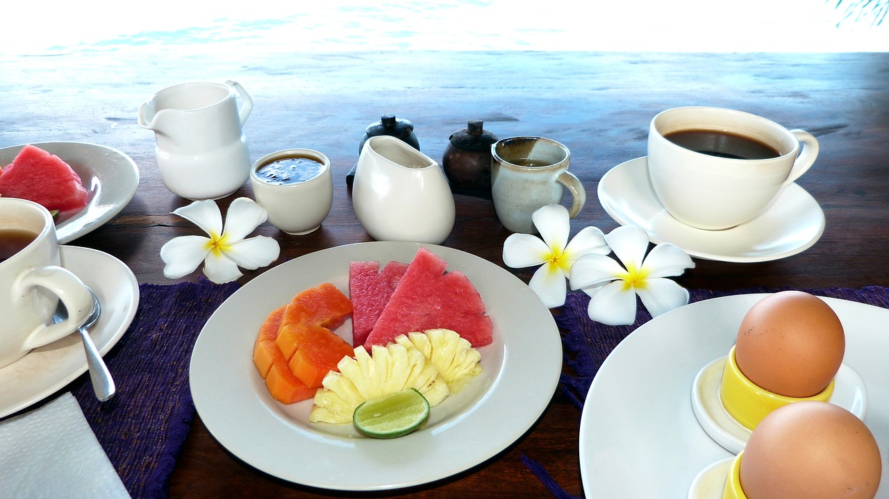 a table topped with plates of food and cups of coffee, by Judith Gutierrez, flickr, dau-al-set, tropical fruit, bali, plumeria, on the ocean