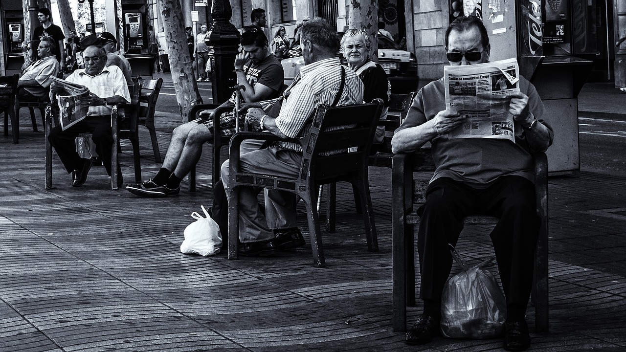 a group of people sitting next to each other on a sidewalk, a photo, by Joze Ciuha, newspaper style, barcelona, old man, near the sea