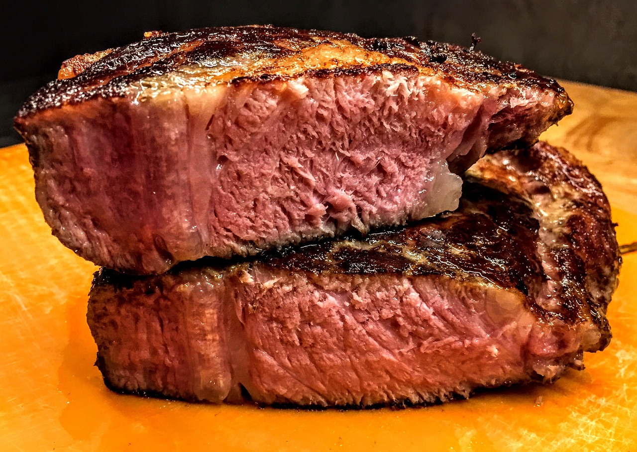 a close up of a piece of meat on a cutting board, a picture, by Matt Cavotta, red and orange colored, steak, gooey, stacked