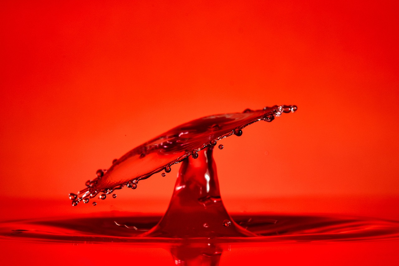 a splash of water on top of a red surface, art photography, vibrant orange background, shot with a canon 20mm lens, amazing photo, wallpaper - 1 0 2 4