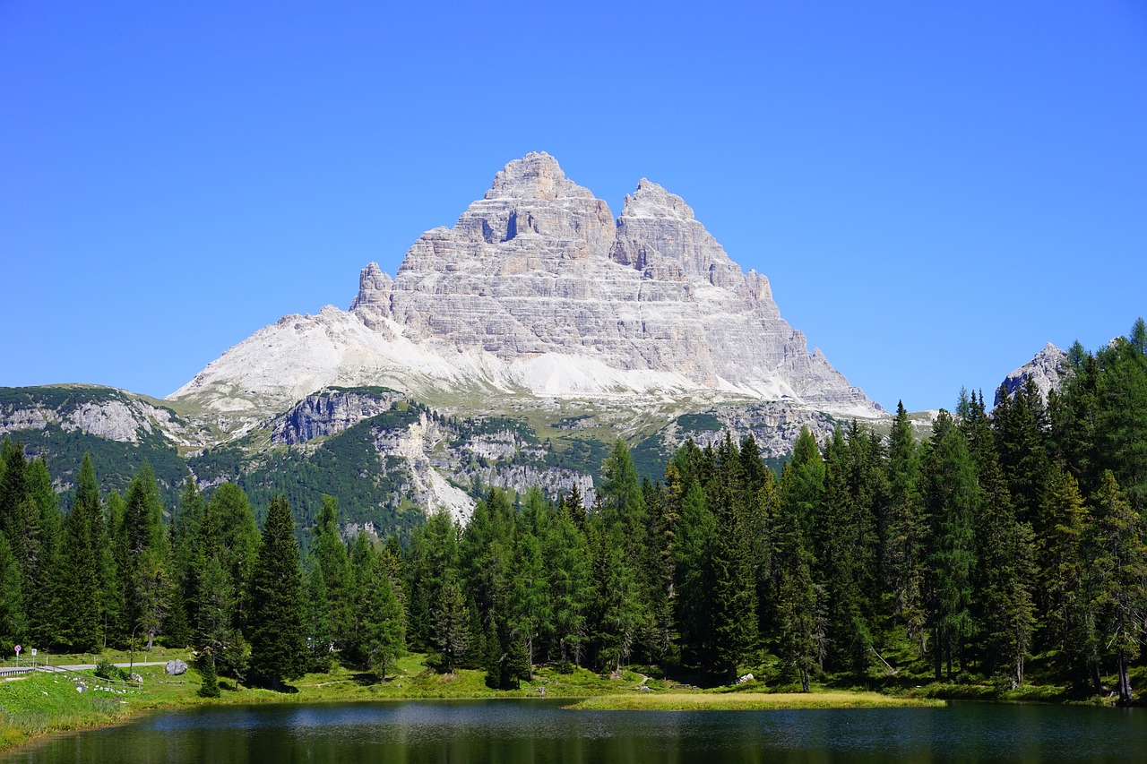 a body of water with a mountain in the background, a photo, by Carlo Martini, shutterstock, build in a forest near of a lake, limestone, high elevation, peak experience ”