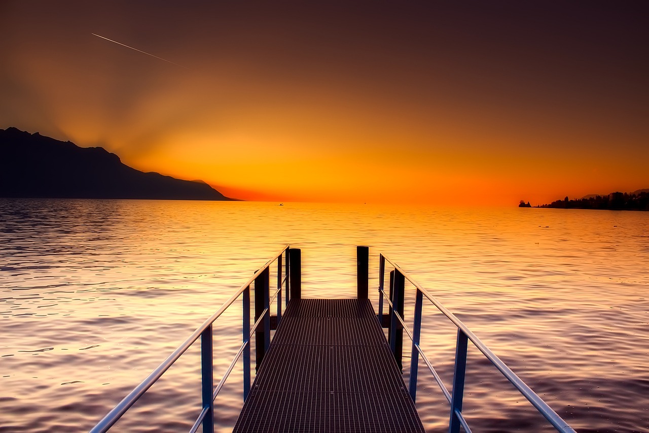 a dock in the middle of a body of water, a picture, by Luca Zontini, shutterstock, orange skies, leading to a beautiful, deck, very beautiful photo