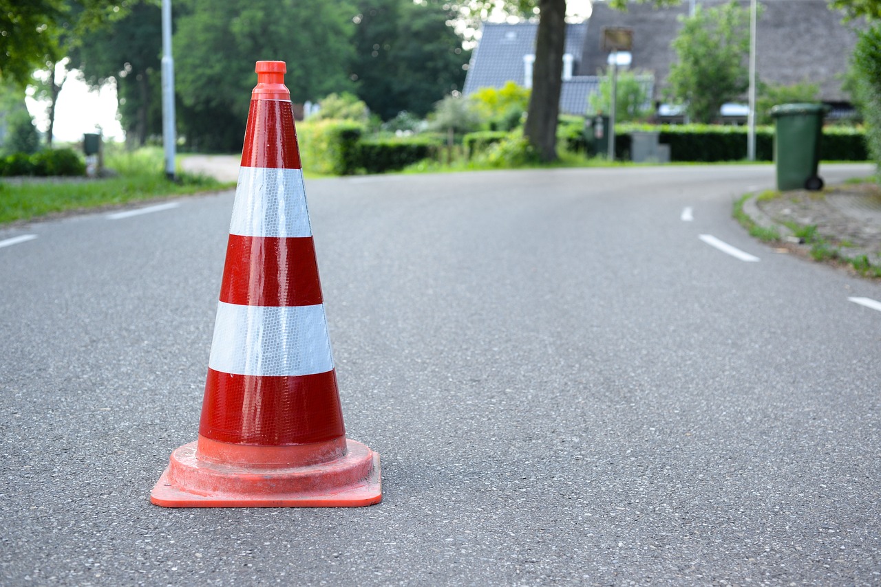 a red and white traffic cone sitting on the side of a road, a photo, by Schelte a Bolswert, shutterstock, maintenance photo, b - roll, handmade, stock photo