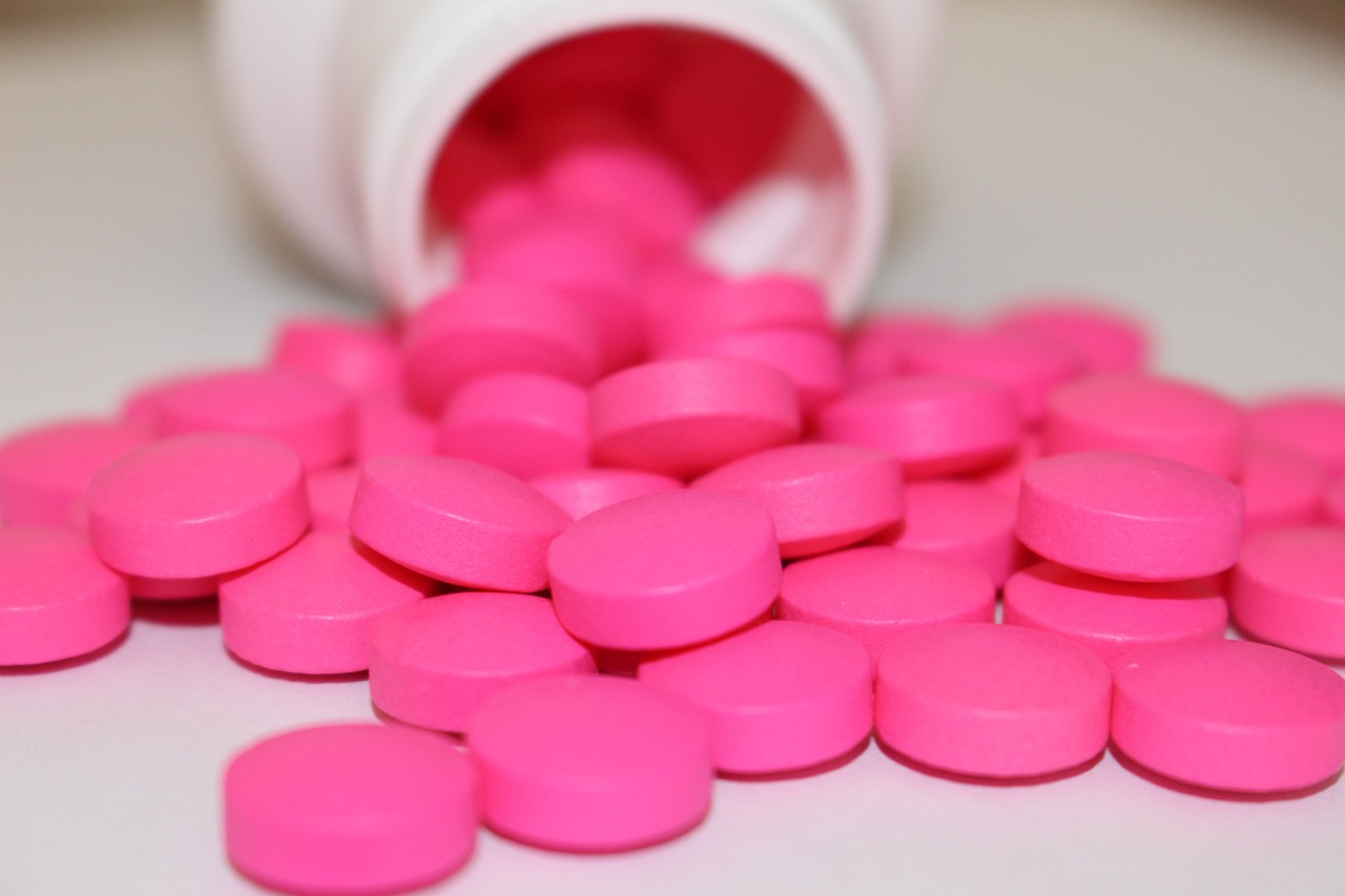 a close up of pink pills spilling out of a bottle, a picture, plasticien, hot pink, soft pads, wide shot photo, shoulder
