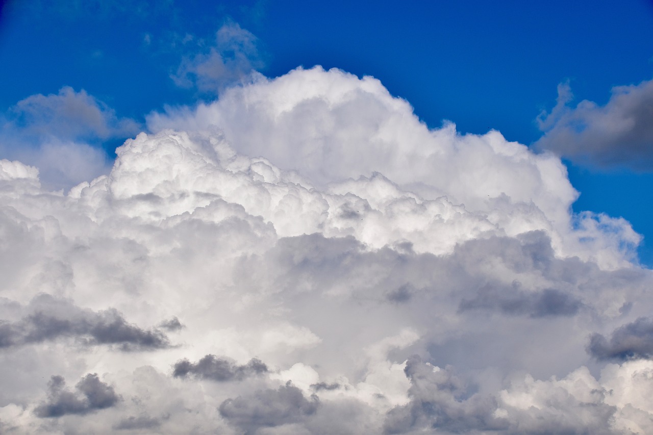 a plane flying through a cloudy blue sky, a stock photo, by Hans Schwarz, shutterstock, giant cumulonimbus cloud, a close up shot, layered stratocumulus clouds, stock photo