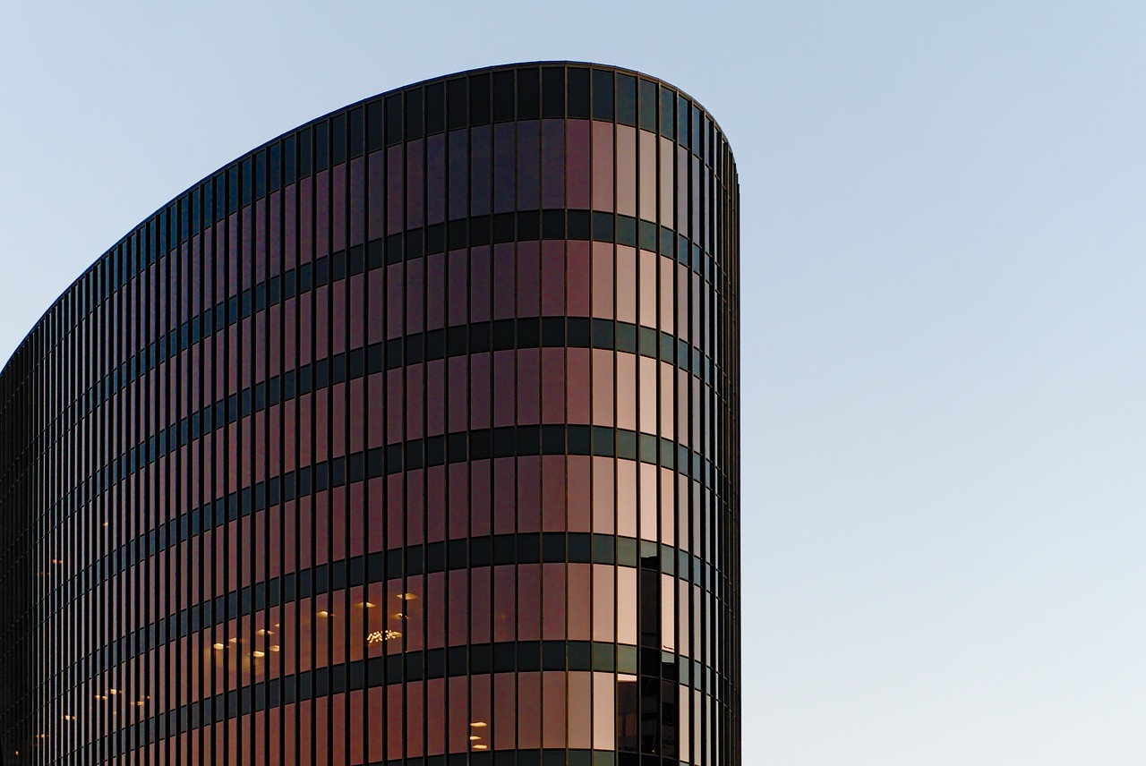 a tall building with a clock on top of it, a stock photo, inspired by David Chipperfield, flickr, brown and pink color scheme, curved lines, color ( sony a 7 r iv, paler. millions of glass-walled