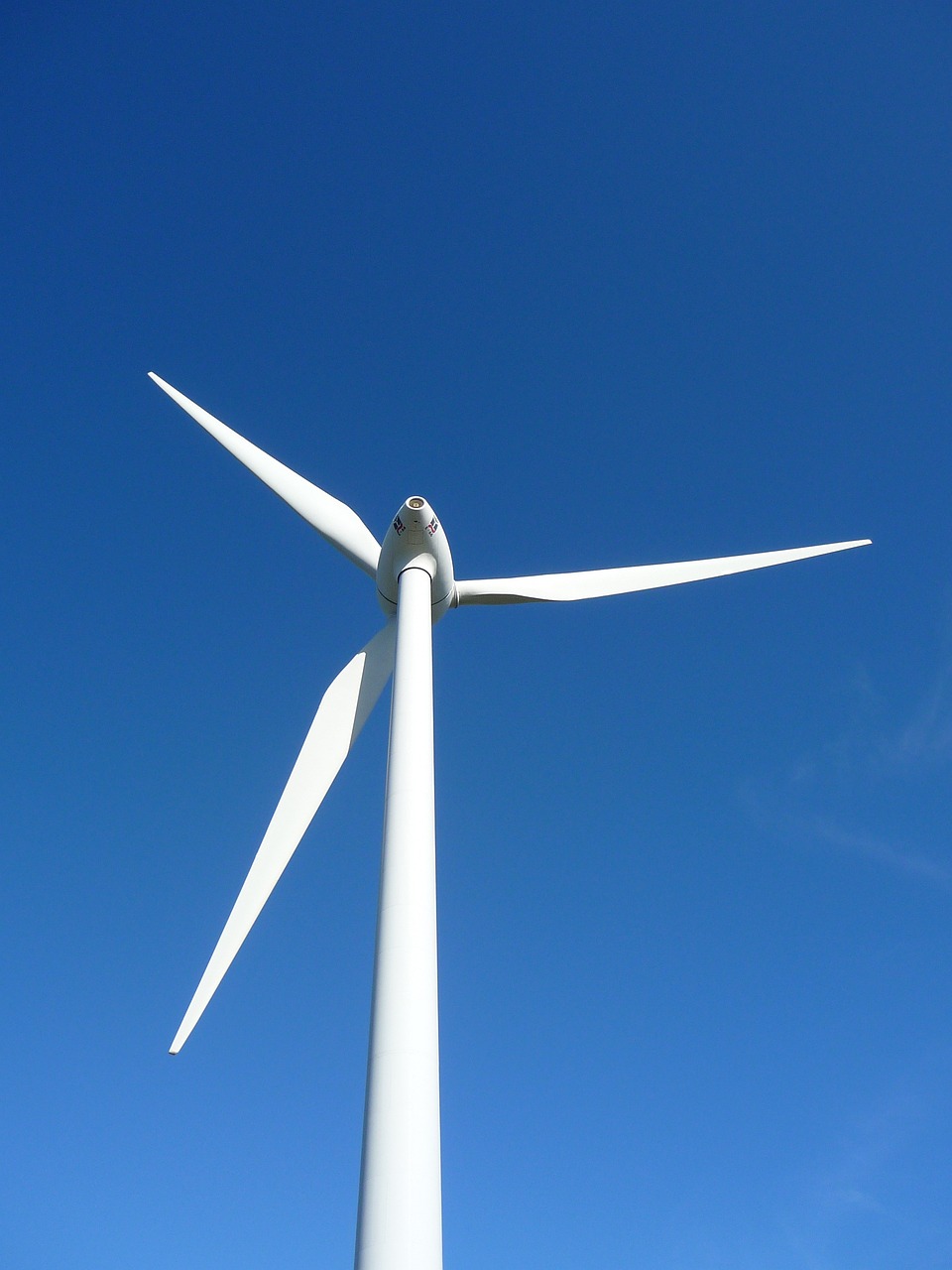 a close up of a wind turbine against a blue sky, by Robert Brackman, flickr, hurufiyya, striking pose, true realistic image, looking partly to the left, stock photo