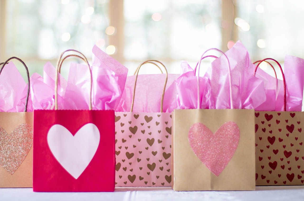 a group of bags sitting on top of a table, by Juliette Wytsman, shutterstock, pink hearts in the background, presents, high quality product photo, istockphoto