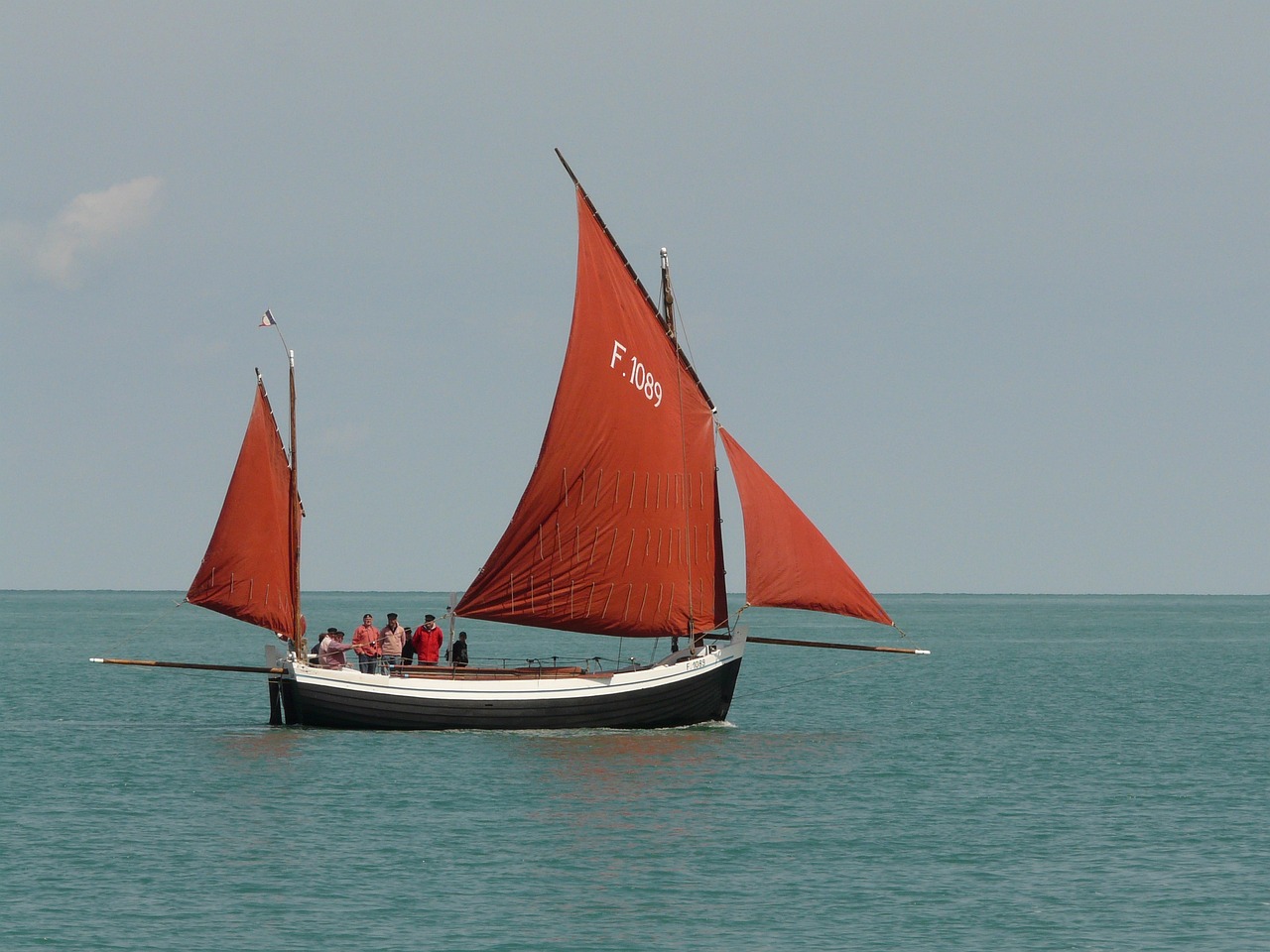 a red sail boat in the middle of the ocean, by Edward Corbett, flickr, figuration libre, dunkirk, brown, festival, round-cropped