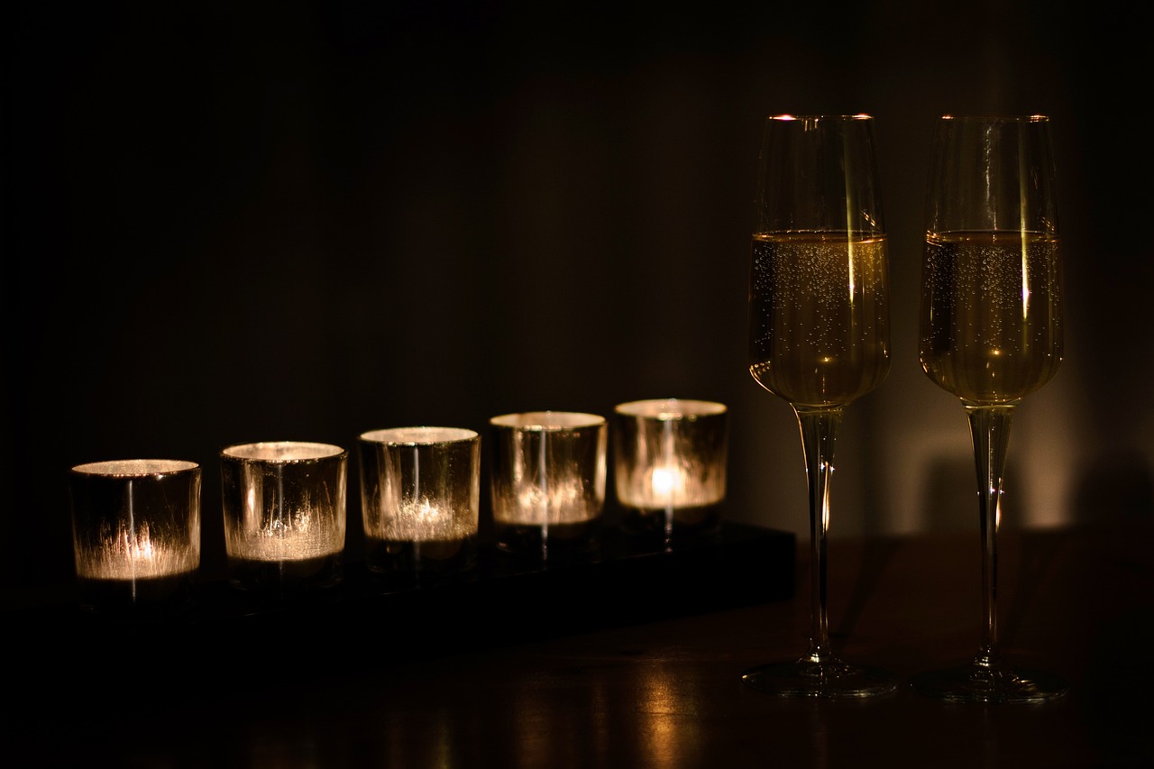 a couple of champagne glasses sitting on top of a table, a still life, pexels, romanticism, dark tones and candlelight, istock, relaxing atmosphere, dark and beige atmosphere