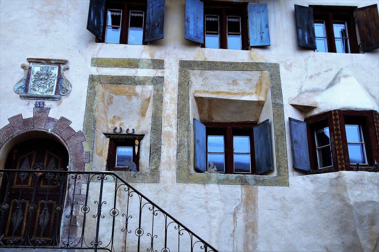 a building with blue shutters and a clock on the wall, inspired by Rudolf Ernst, flickr, stairs and arches, in the dolomites, impasto, window reflections