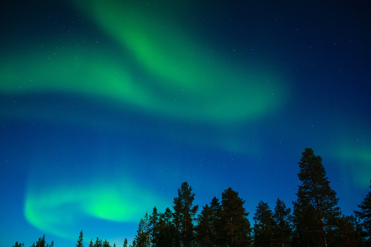 a group of people standing on top of a snow covered slope, by Anato Finnstark, pexels, northern lights in space, green blue red colors, in the forest at night, stock photo