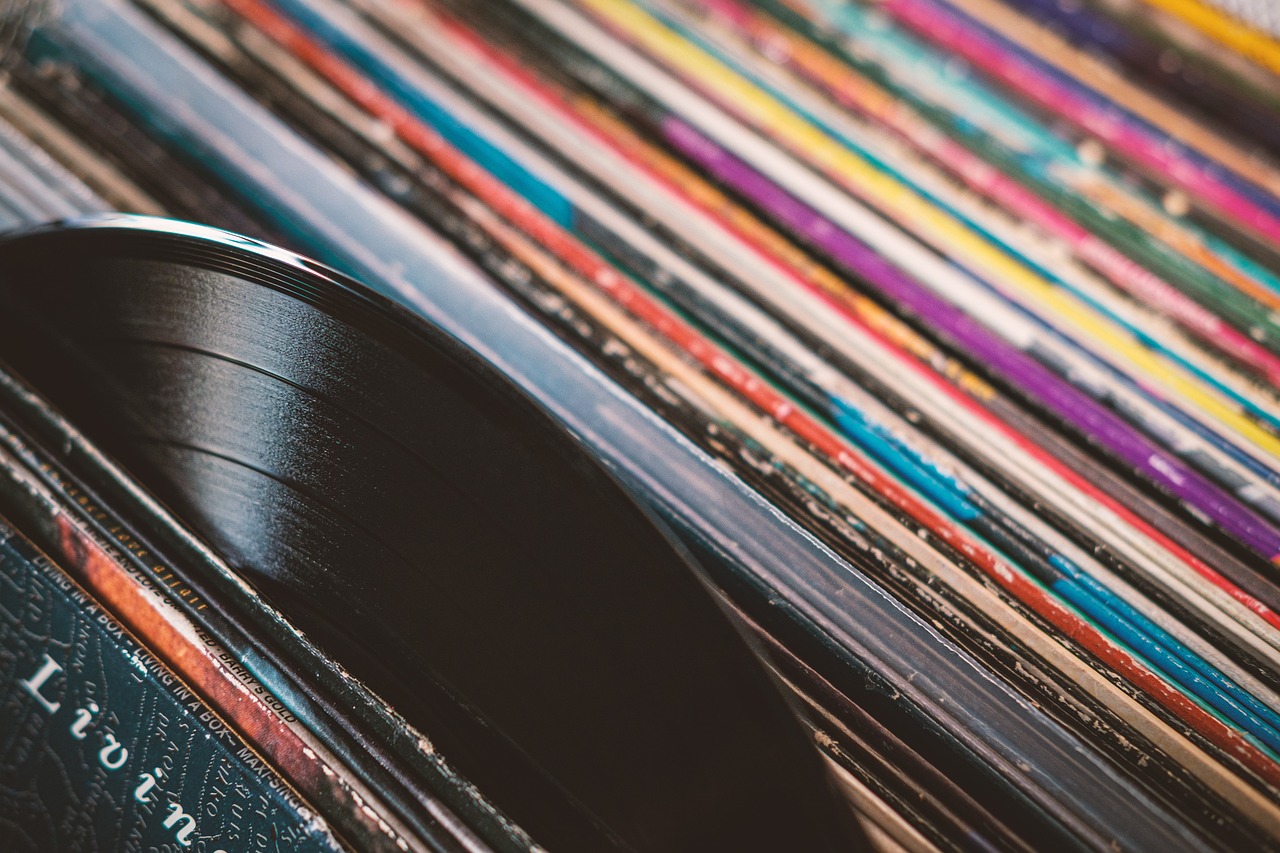 a pile of vinyl records sitting on top of a table, an album cover, pexels, detailed photo of an album cover, multi - coloured, neck zoomed in, thumbnail