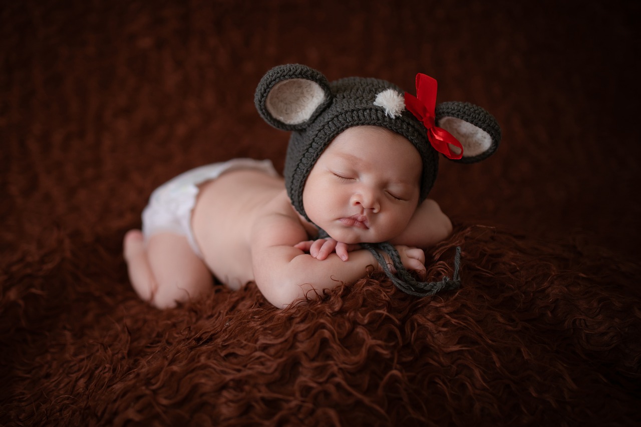 a baby laying on top of a brown blanket, inspired by Anne Geddes, flickr, cute ears, red hat, beautiful mouse - girl, anna nikonova