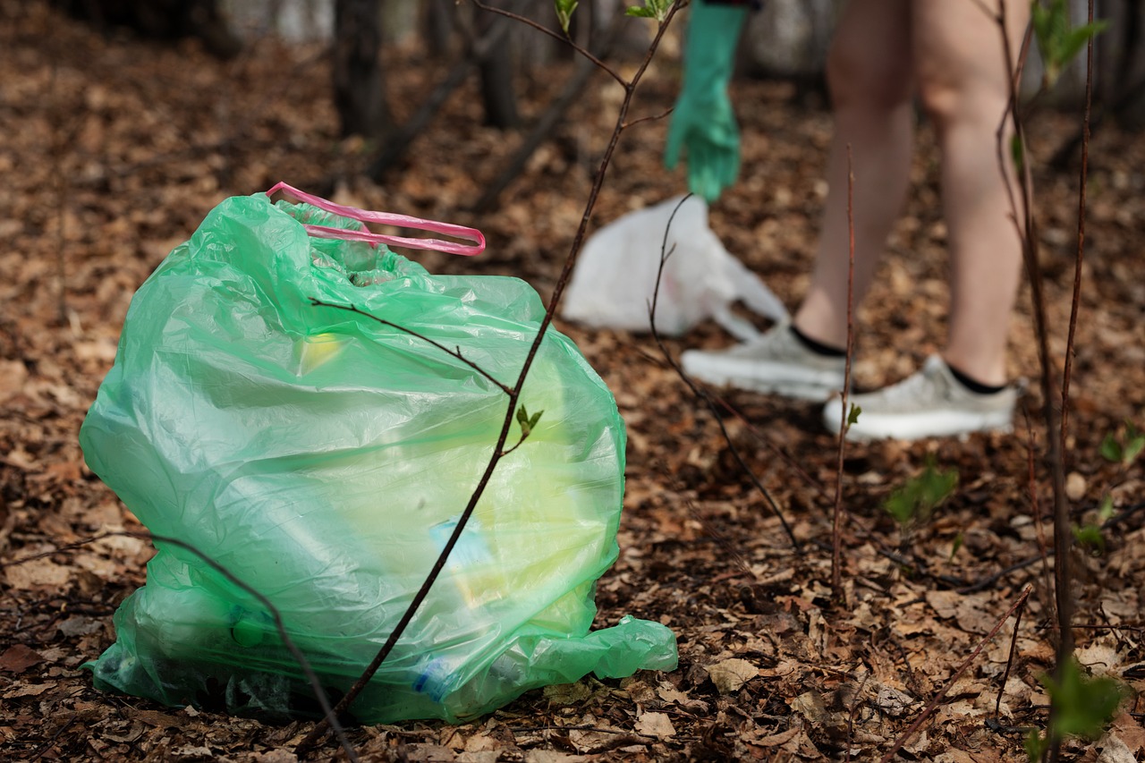 a person standing next to a bag of trash in the woods, a picture, by Stefan Gierowski, shutterstock, plasticien, plastic texture, people at work, close-up shot, stock photo