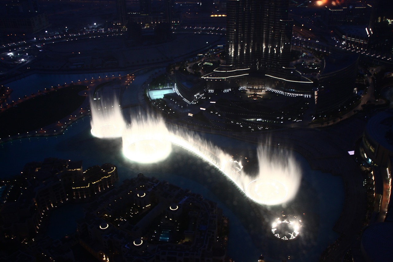 a water fountain in the middle of a city at night, by Bernardino Mei, hurufiyya, beautiful lighting uhd, helicopter view, dubai, stunning screensaver