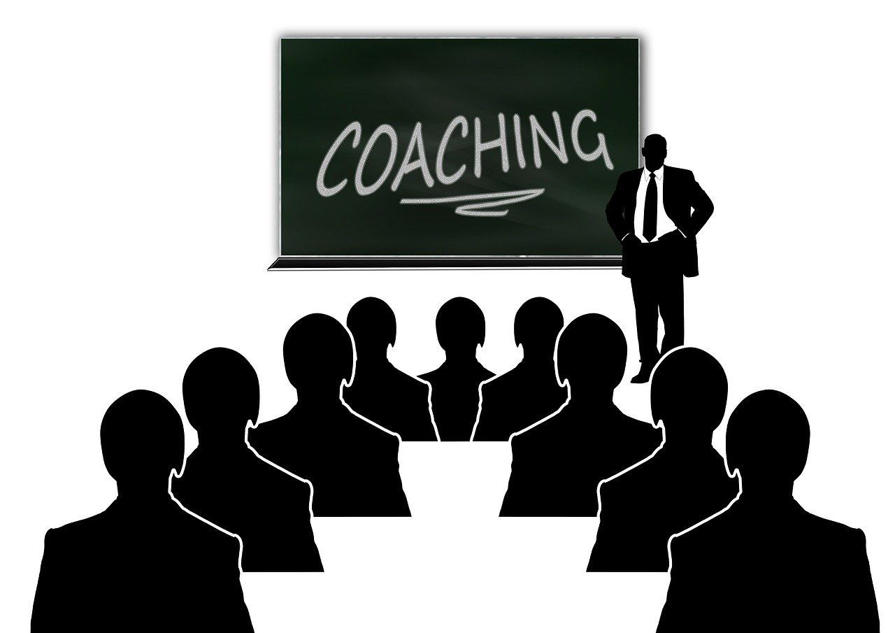 a man standing in front of a blackboard with coaching written on it, by Mirko Rački, pixabay, black on white background, a group of people, pictogram, seen from below