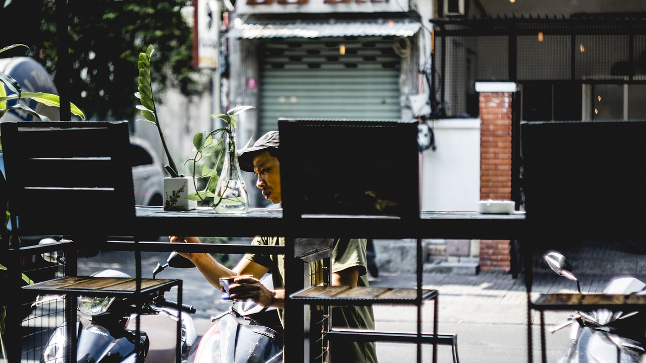 a person sitting at a table on a scooter, unsplash, shanghai, urban jungle, tending on arstation, cafe