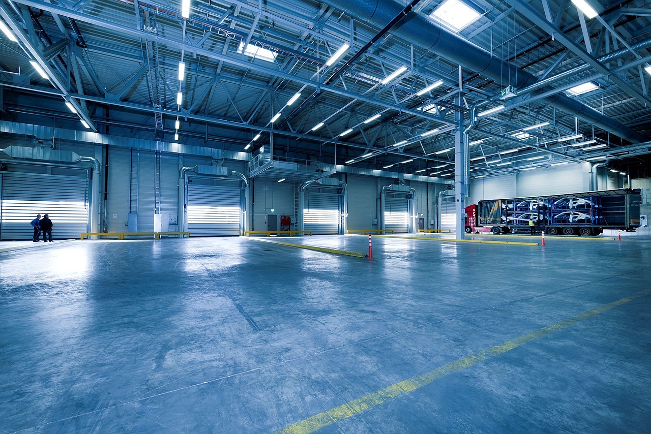 a large warehouse with a truck parked inside of it, a portrait, by Richard Carline, shutterstock, light and space, open shiny floor, brightly lit blue room, maintenance area, interior of a small