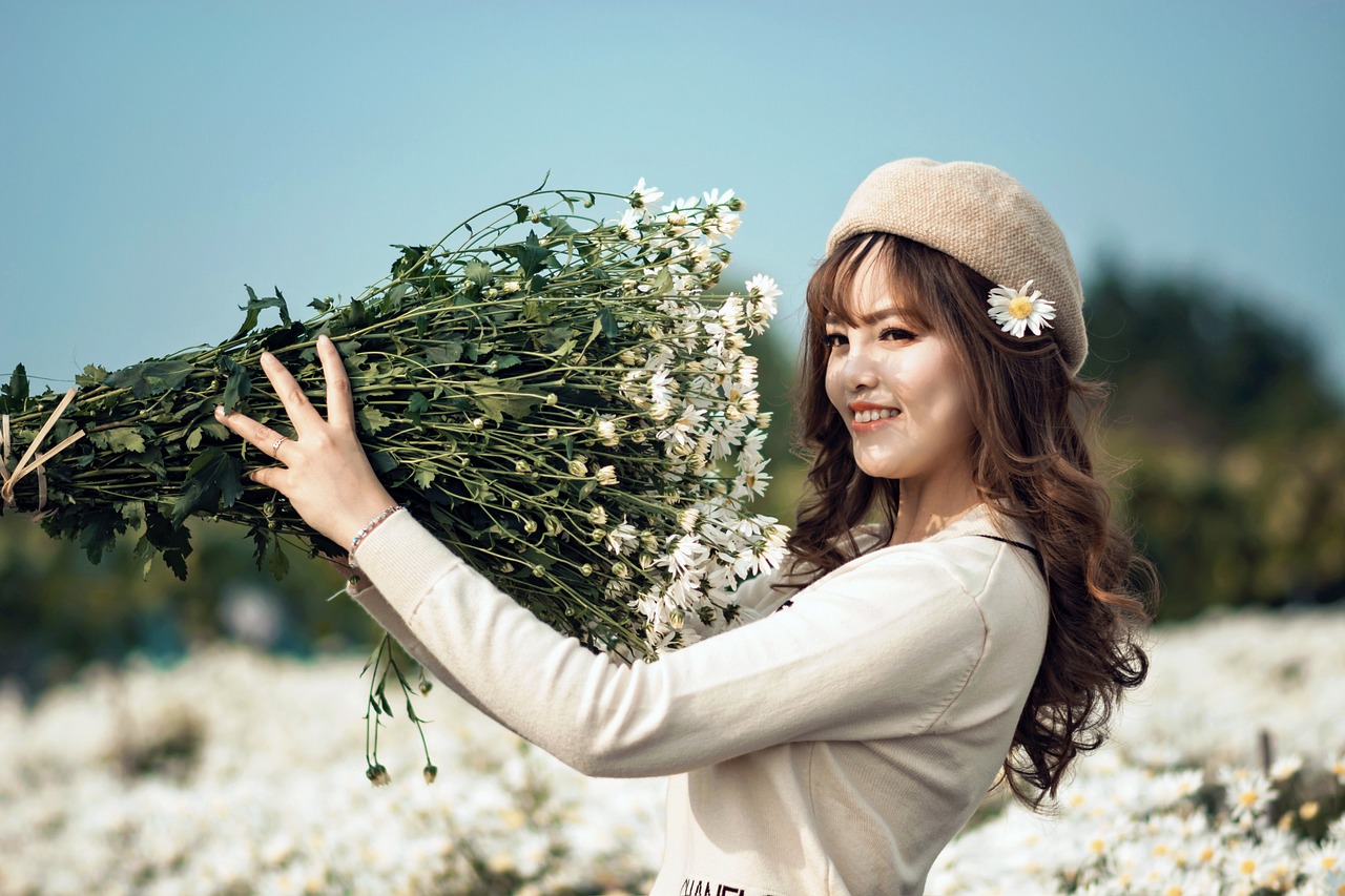 a woman holding a bunch of flowers in a field, a picture, by Tan Ting-pho, visual art, white flower, young and cute girl, wearing wool hat, high quality image