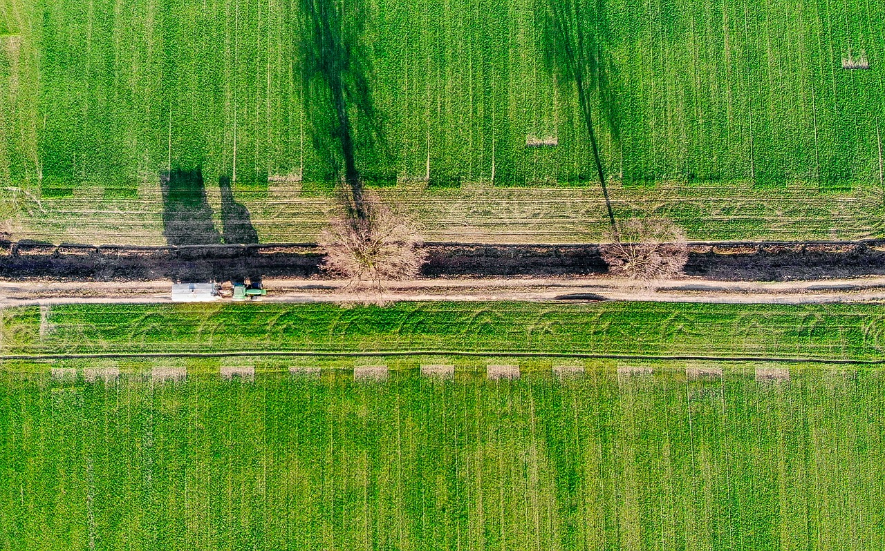 a truck driving down a road next to a lush green field, by Richard Carline, drone photograpghy, trenches, water pipe, boring