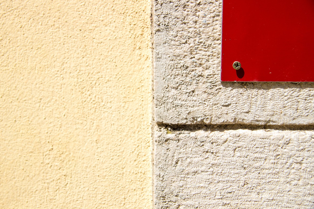 a red sign sitting on the side of a building, a minimalist painting, postminimalism, walls with tone of yellow, closeup photo, three colors, diptych