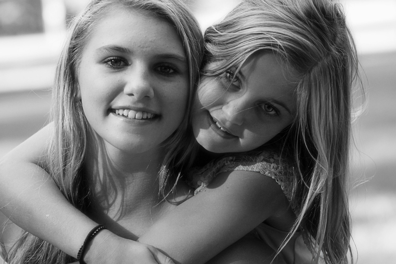 a black and white photo of two girls hugging each other, a black and white photo, flickr, one is blond, smiling at the viewer, july 2 0 1 1, 1 3 5 mm nikon portrait