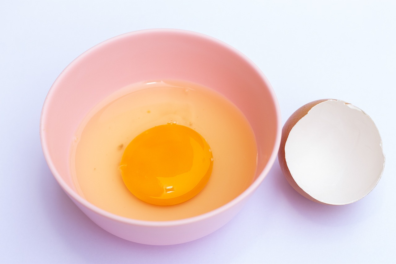 an egg in a bowl next to a broken egg, by Maeda Masao, shutterstock, close-up product photo, pink and yellow, half body photo, mixing