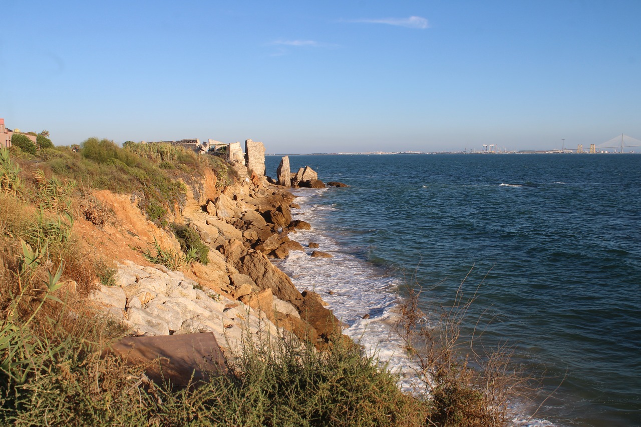 a group of people standing on top of a cliff next to the ocean, shutterstock, les nabis, city wall, farol da barra, usa-sep 20, ruins around