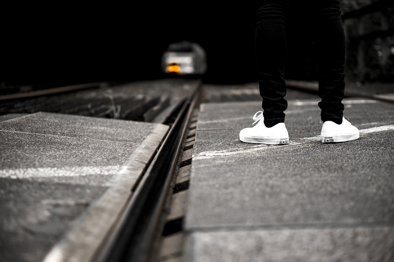 a person standing on top of a train track, a picture, by Niko Henrichon, white shoes, standing with a black background, standing on street corner, dof wide