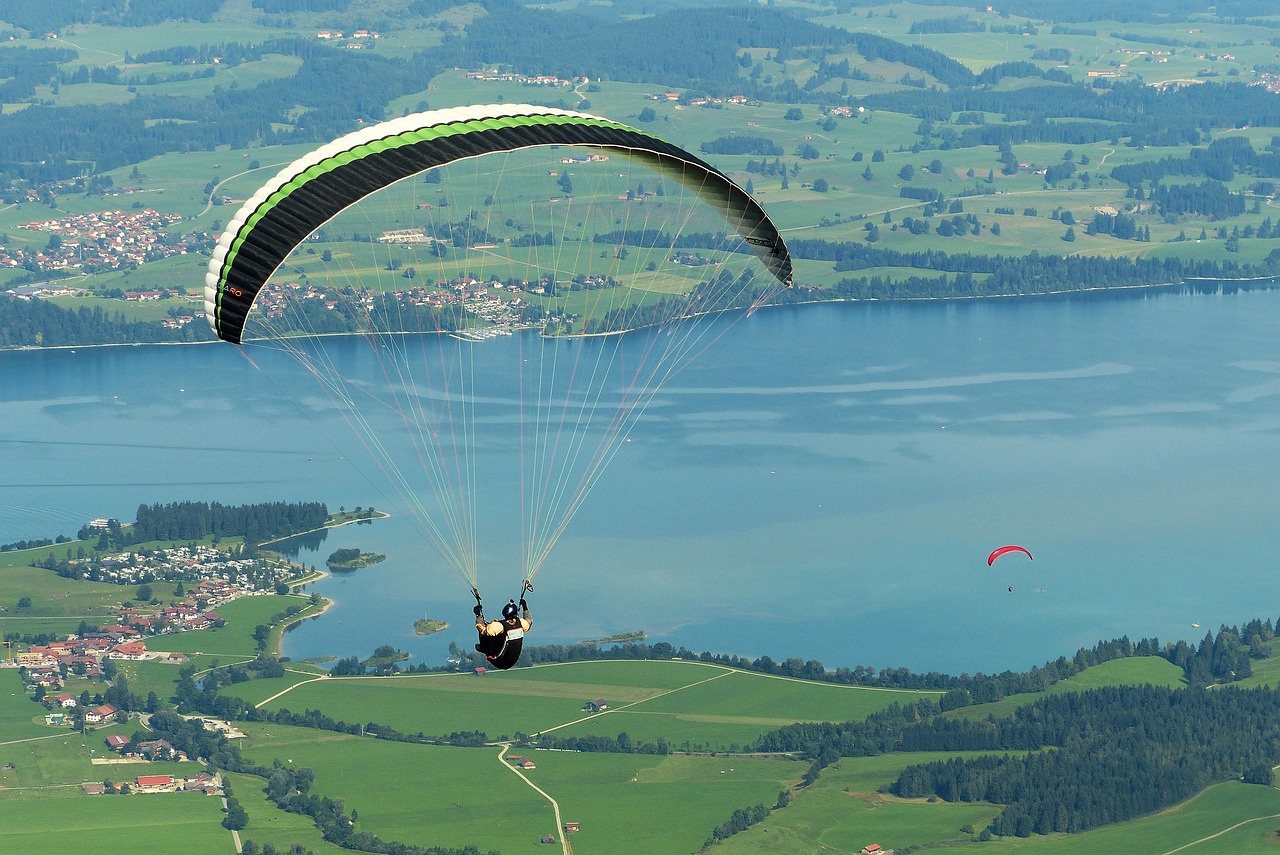 a person that is in the air with a parachute, by Juergen von Huendeberg, pixabay, hurufiyya, panoramic shot, lakeside, screen cap, wikimedia commons