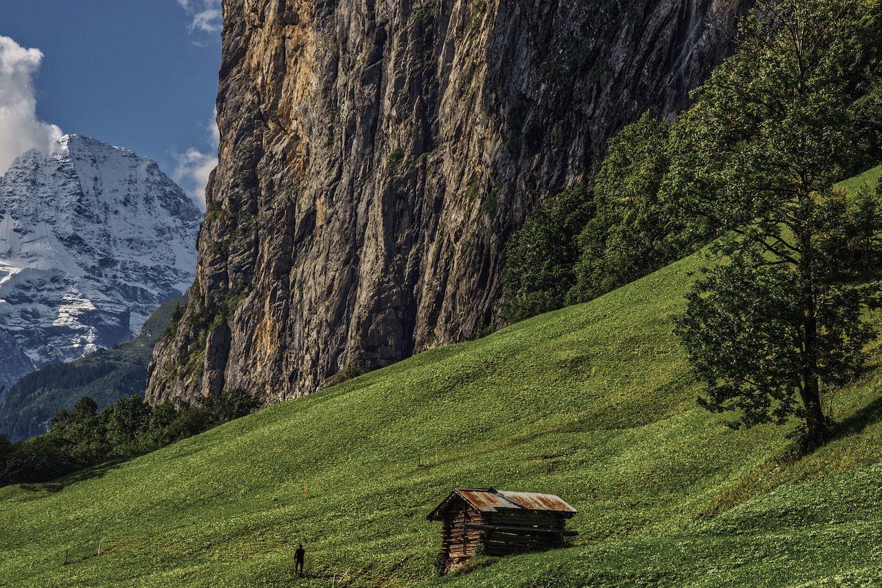 a small cabin sitting on top of a lush green hillside, a picture, by Matthias Weischer, lauterbrunnen valley, climber, very very well detailed image, background mountains